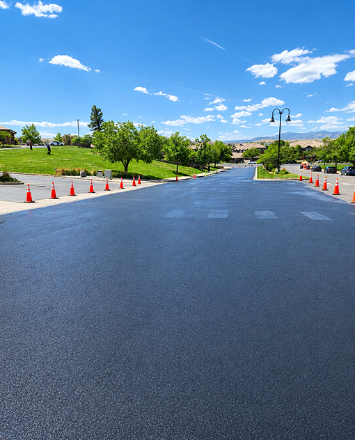 Recently sealcoated asphalt roadway with a smooth black finish completed by Prime Line Company